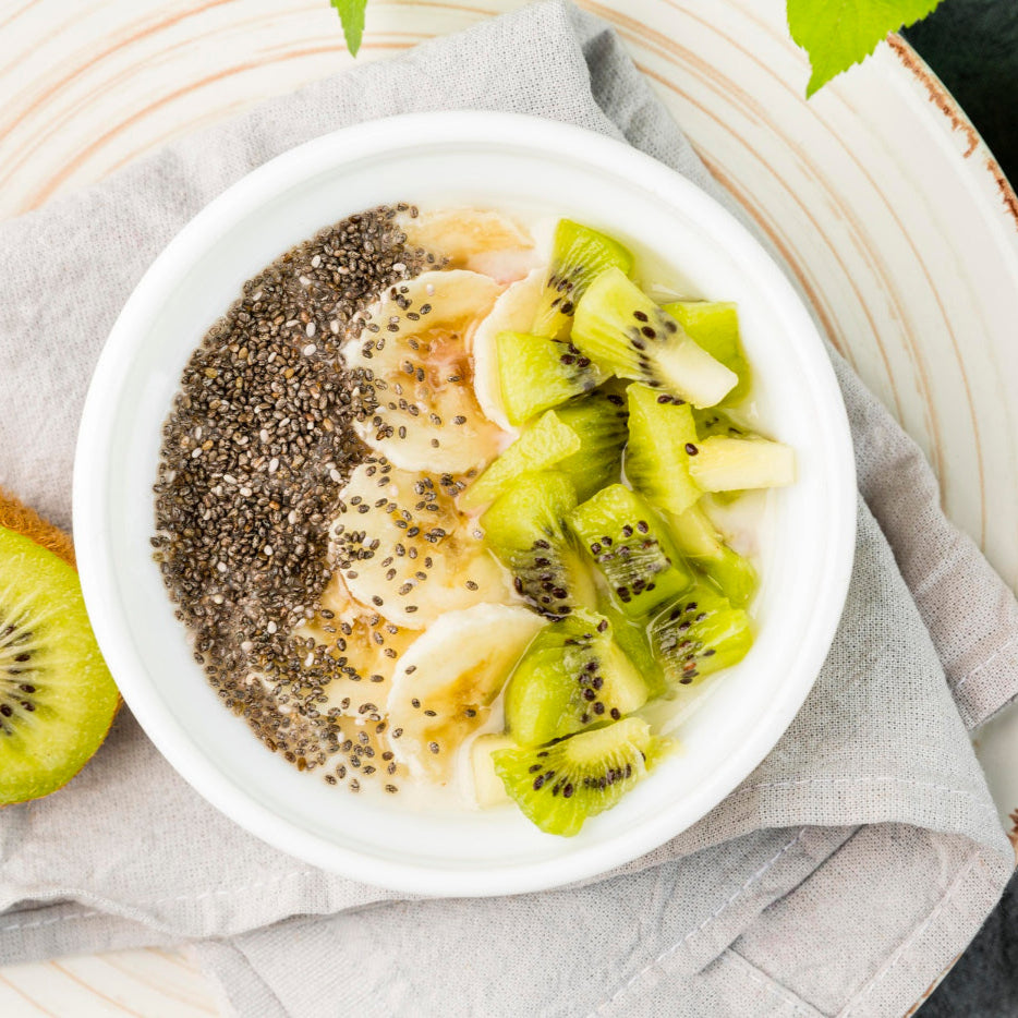 Fruit bowl with kiwis, chia seeds, and other fruits on a light background