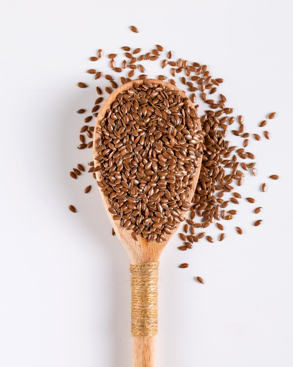 Wooden spoon filled with flaxseeds on a white background